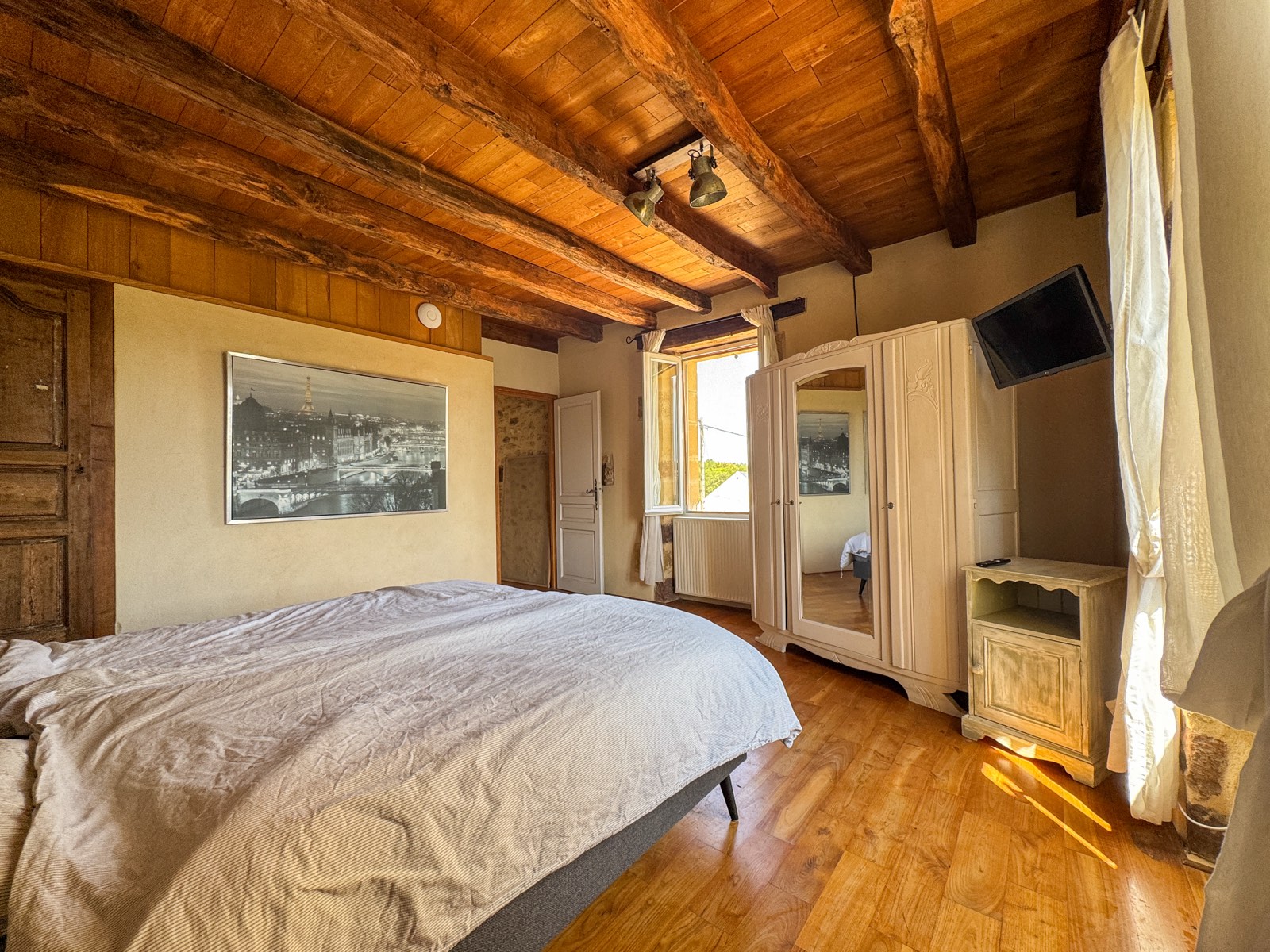 Slaapkamer met tweepersoonsbed en houten balkenplafond in Moulin Noix