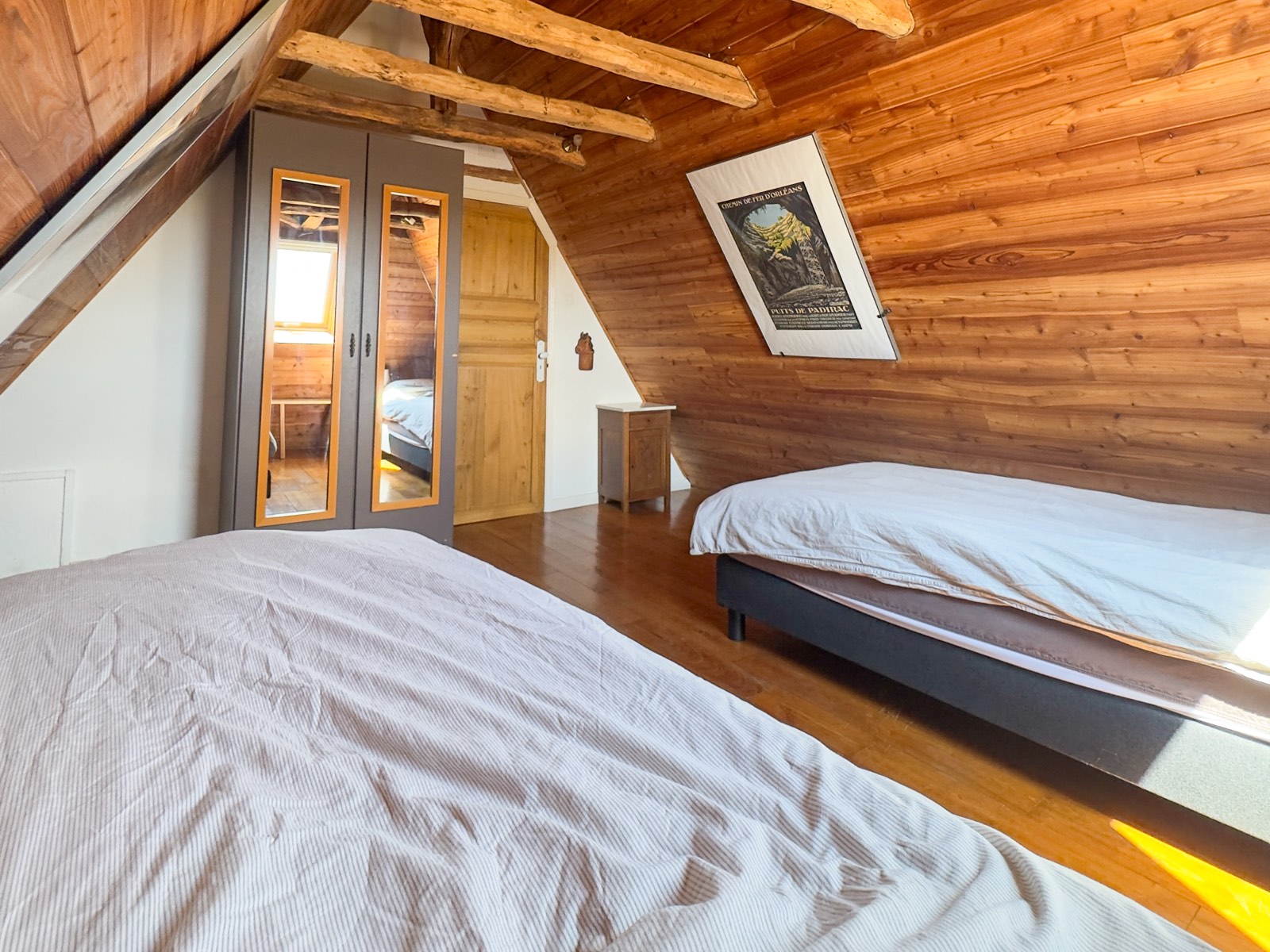 Zolderslaapkamer met tweepersoonsbed en houten wanden in Moulin Noix