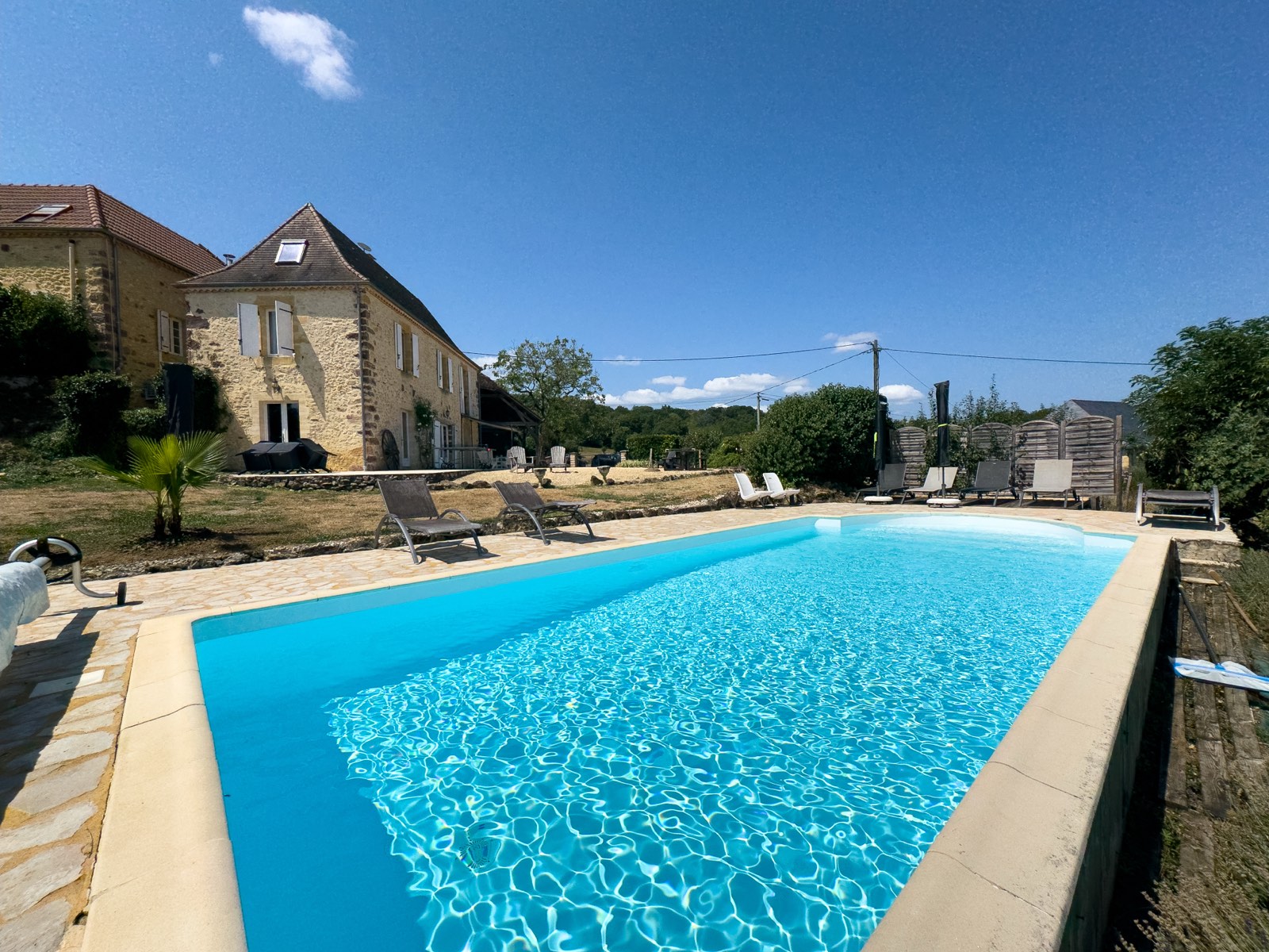 Privezwembad met vakantiehuis Moulin Noix op de achtergrond in de Dordogne